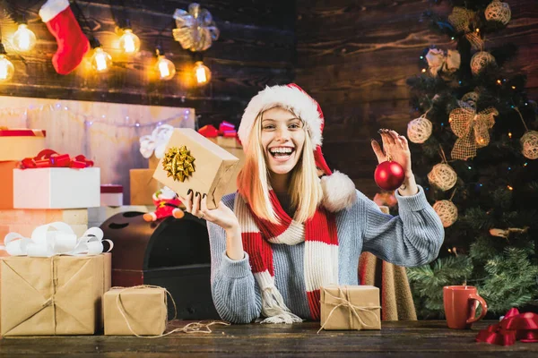 Gülümseyen genç bir kadının portresi. Kış kadını kırmızı Noel Baba şapkası takıyor ve hediyesini tutuyor.. — Stok fotoğraf