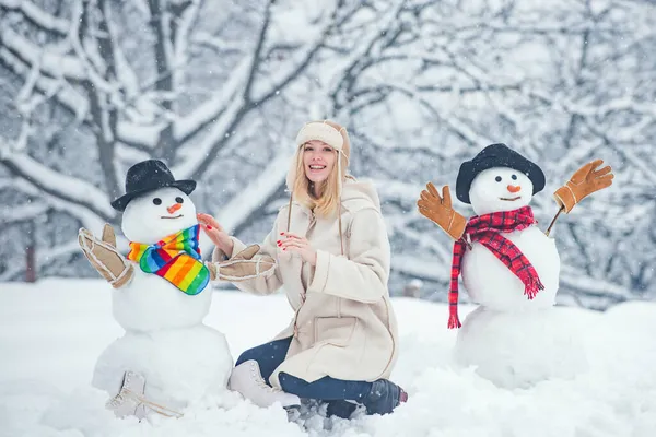 Téli lány. Boldog fiatal nő játszik egy hóemberrel egy havas sétán. Téli érzelem. Fiatal nő téli portré. Karácsonyi emberek. — Stock Fotó