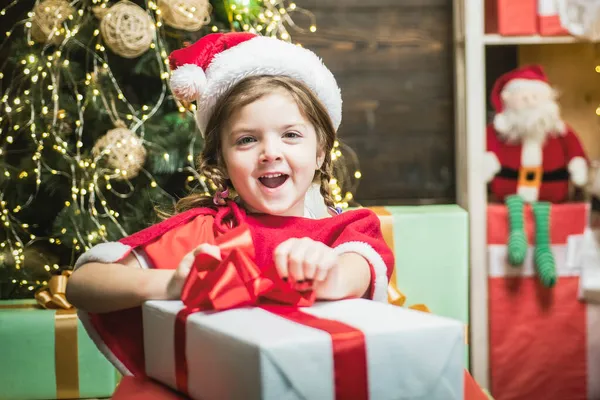 Entusiasmado criança bonito abrir um presente de Natal. Natal criança menina segurando uma caixa de presente vermelho. — Fotografia de Stock