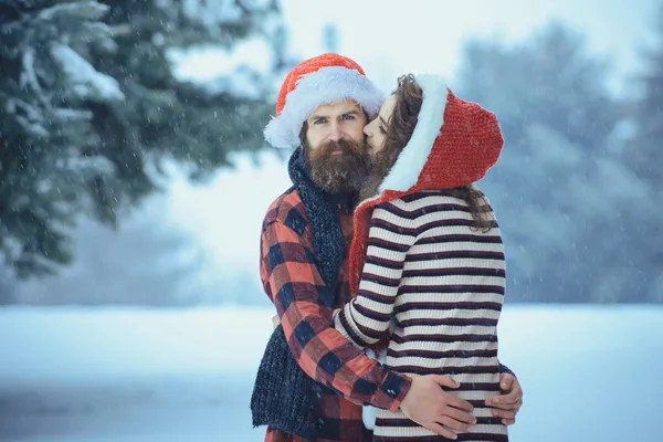 Pareja de Navidad de hombre y mujer felices. Pareja enamorada del sombrero rojo de Santa Claus en invierno al aire libre. Vacaciones de invierno y vacaciones — Foto de Stock
