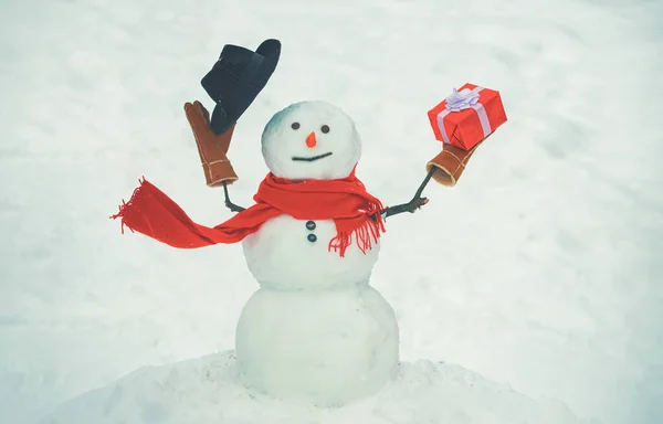 Hóember sapkával és sállal télen a szabadban. Üdvözlő hóember. Boldog hóember áll a téli karácsonyi táj. Design ajándékdobozok Kézzel készült hóember. — Stock Fotó