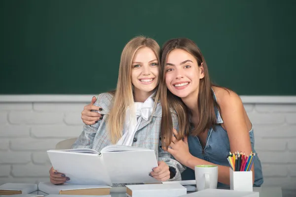 Šťastní usměvaví studenti dívky objímání a objímání ve třídě na vysoké škole. — Stock fotografie