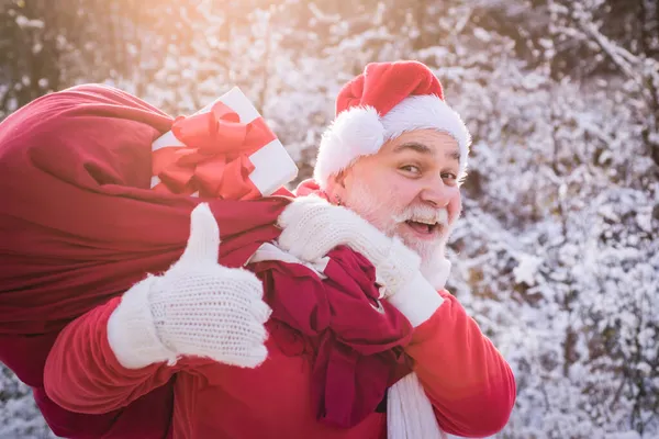 Papá Noel viene con el pulgar hacia arriba en el bosque de nieve, los pulgares superiores hacia arriba signo. —  Fotos de Stock