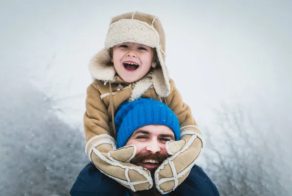 Táta a kluk se usmívají a objímají. Otec vezl syna zpátky do zimního parku. Veselé Vánoce a šťastný nový rok. Portrét šťastného otce a syna. — Stock fotografie