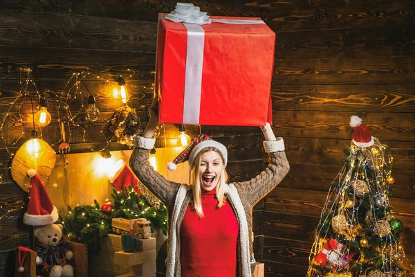 Blonde drôle dans le chapeau de Noël et cadeaux célébrant Noël vacances tenir grande boîte sur la tête. — Photo