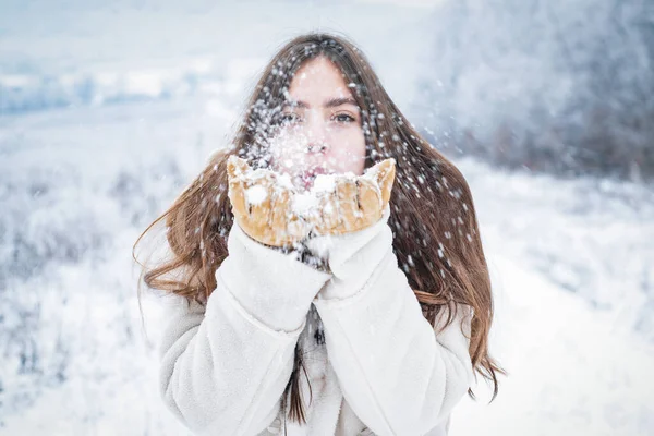 Szczęśliwa zima dziewczyna dmuchać śnieg. Młoda kobieta w ferie zimowe. — Zdjęcie stockowe