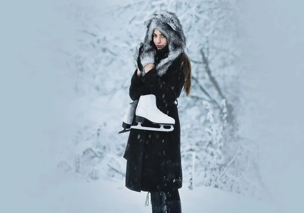 Flicka med konståkning vid träd i snö. Kvinna med skridskoskor i vinterkläder i snöig skog. Vintersemester, semester och livsstil — Stockfoto