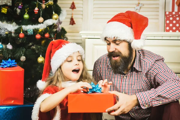 Gelukkig vader en dochter kind met cadeau in kerstmuts bij kerstboom. Wintervakantie met het gezin en gelukkig Nieuwjaar — Stockfoto