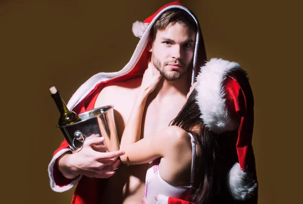 붉은 크리스마스 때 코르셋을 입고 산타 코트를 입은 근육질 남자를 껴안고 있는 섹시 한 커플 — 스톡 사진