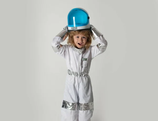小さな男の子は宇宙飛行士になって宇宙に飛び込むことを夢見ています。宇宙服やヘルメットの夢のコスモスの子供たち。面白い驚きの男の子宇宙飛行士. — ストック写真