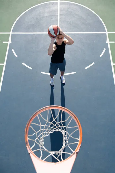 Giocatore di basket che spara palla in cerchio campo esterno. Gioco giovanile urbano. Concetto di successo sportivo, punti e vittorie. — Foto Stock