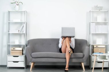 Seksi bacaklı baştan çıkarıcı sekreter ofiste kanepede oturur. Seksi iş kadını yüzünü dizüstü bilgisayarla kapatıyor. Şehvetli kız çalışanı. Güzel sekreter bacakları.