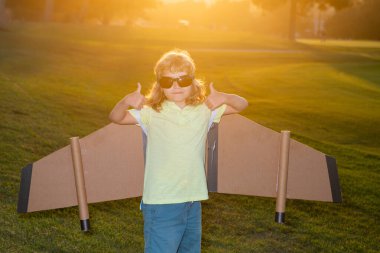 Pilot gözlüklü çocuk oyuncak jetpack ile oynuyor. Çocuk pilot astronot ya da uzay adamı uçmayı hayal eder. Karton kanatlarla uçan havacı çocuk..