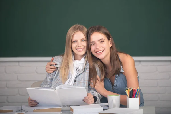 Belle studentesse che si abbracciano e si abbracciano in classe al college scolastico. — Foto Stock