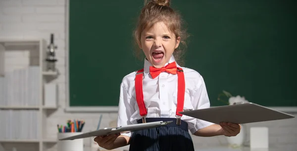 反対距離教育で悪い子の生徒。怒っている子供は学校でオンラインノートパソコンを壊した。損傷したコンピュータ技術を粉砕する。コンピュータクラスの遠隔学習に関する子供の問題. — ストック写真