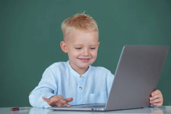 Lindo niño sonriente usando computadora portátil, niño estudiando a través de e-learning en línea. Pequeño programador divertido. — Foto de Stock