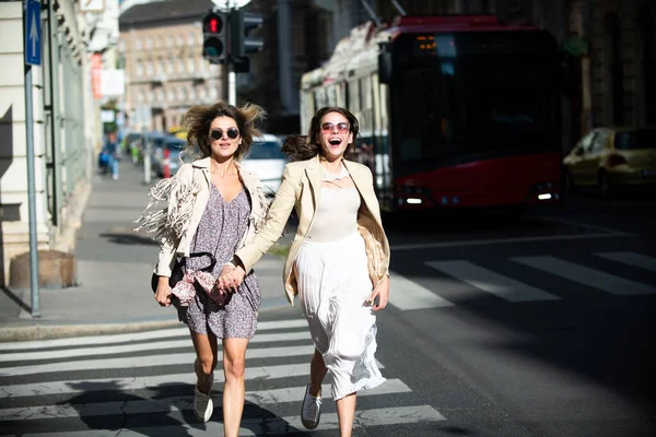 Két izgatott, boldog nő együtt rohangál az utcán. Vicces nyaralás, romantikus utazás. — Stock Fotó