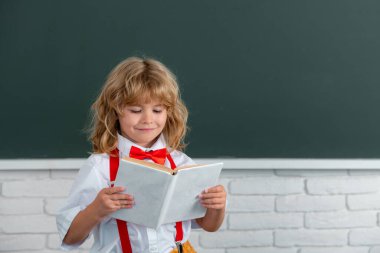 Okullu çocuk sınıfta bir kitap okuyor. Okuldaki sevimli çocuk. Çocuk sınıfta tahtayla ilgili bir şeyler öğreniyor. Okula dönüyorum, okuldaki ilk günüm..