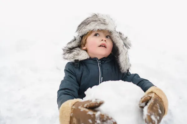 Drôle de garçon posant sur le temps d'hiver. Enfant jouant avec boule de neige. — Photo