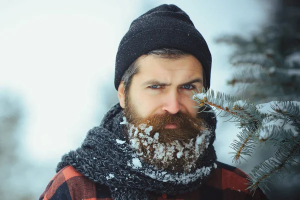 Hipster navideño. Retrato de invierno de cerca. Hombre con barba en el bosque de invierno con nieve — Foto de Stock