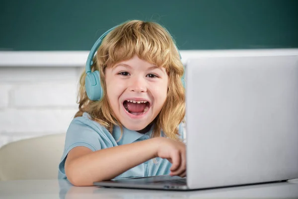 Muchacho inteligente emocionado de la escuela, alumno sorprendido lleva auriculares escribir en el ordenador portátil, escuchar el uso de la lección de audio ordenador. — Foto de Stock