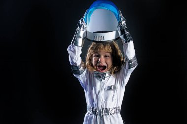 Siyah arka planda miğfer tutan, uzay kıyafetli, heyecanlı, çocuk bir uzaylı..