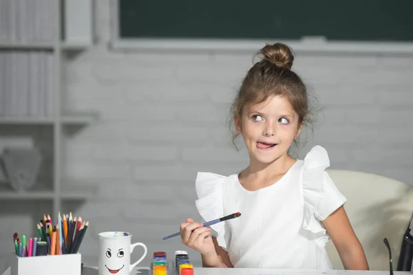 Vicces kislány gyermek festmény festékek szín és ecset. Rajzóra az iskolában. Gyerekkori tanulás, gyerekek művészeti készségei. — Stock Fotó