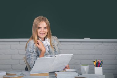 Lisenin ya da üniversitenin sınıfında ders kitabı okuyan kız öğrenci.