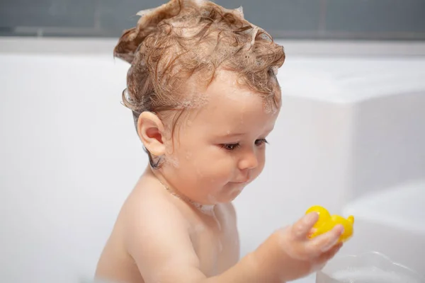 Tvättar bedårande bebis i badrummet. Grabben med tvål suger på håret och badar. Närbild porträtt av leende barn, hälsovård och barn hygien. Badkar för barn. — Stockfoto