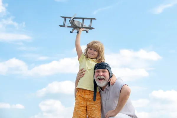 할아버지와 손자는 장난감 제트 팩 비행기를 타고 하늘을 향해 날아간다. 비행기 여행을 꿈꾸는 어린이 비행사. — 스톡 사진