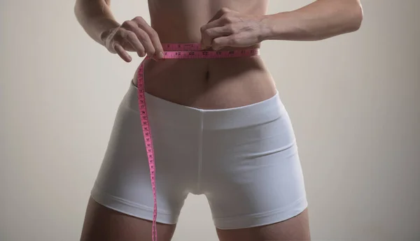 Slanke fit jonge vrouw meten haar dunne taille. — Stockfoto