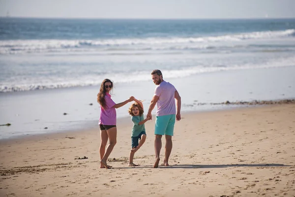 家族でビーチを歩く。砂のビーチを歩く幸せな父、母と息子の子供。子供と夏休み. — ストック写真