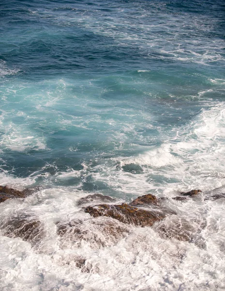 Голубое море и бушующие камни. Волновой спрей над камнями. Скалистое побережье. — стоковое фото