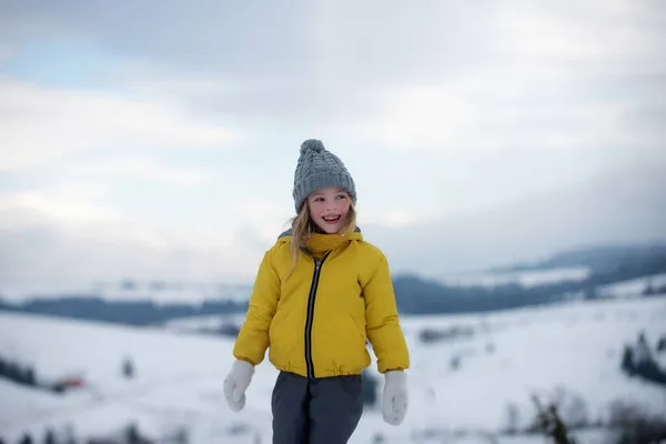 雪の冬の自然上のかわいい女の子。冬服の面白い子供。子供たちは雪の中屋外で遊ぶ。子供クリスマス休暇. — ストック写真