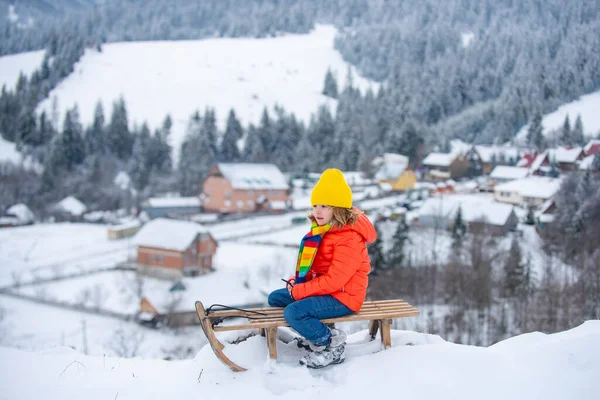 Dítě si užívá sáňkování, sáňkování. Děti si venku hrají ve sněhu. Děti jezdily v zimě na saních do Alp. Venkovní zábava pro rodinnou vánoční dovolenou. — Stock fotografie