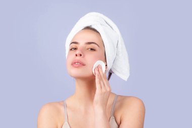 Kafasında banyo havlusu olan genç ve güzel bir kadının yakın çekimi. Stüdyoda izole edilmiş güzel kadın yüzü. Doğal kozmetik ve cilt bakımı. Kaplıca salonundaki güzel kadın.