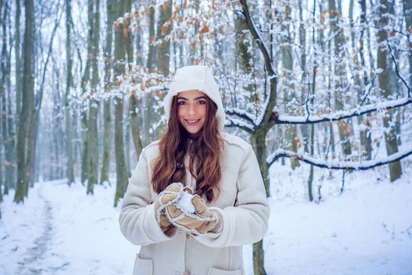 Χειμερινή διασκέδαση. Κορίτσι που παίζει με το χιόνι στο πάρκο. Χειμερινά γυναικεία ρούχα. Χιόνι χειμερινής γυναίκας. — Φωτογραφία Αρχείου