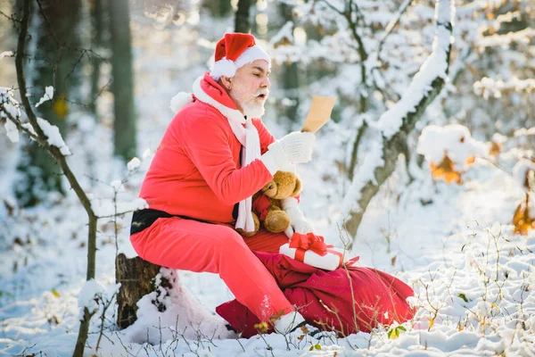 Jultomten läste julönskelista utomhus i snöig skog. Gott nytt år. — Stockfoto