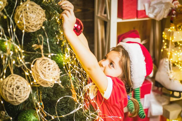 Schattig kind meisje is de kerstboom aan het versieren. Kind versieren kerstboom met bauble. — Stockfoto