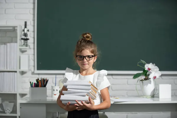 Retrato de bonito, adorável, menina em uniforme escolar em sala de aula. Nerd menina da escola em óculos com livros no quadro negro. — Fotografia de Stock