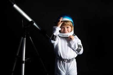 Teleskoplu çocuk kendini uzay kaskı takan bir astronot olarak hayal ediyor. Astronomi ve astroloji kavramı.