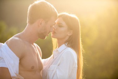 Gün batımında birbirine aşık güzel bir çiftin portresi. Genç şehvetli kız arkadaşı, erkek arkadaşından tutkulu bir öpücük aldığı için mutlu. Yakışıklı genç adam kadınını kucaklıyor ve öpüyor..