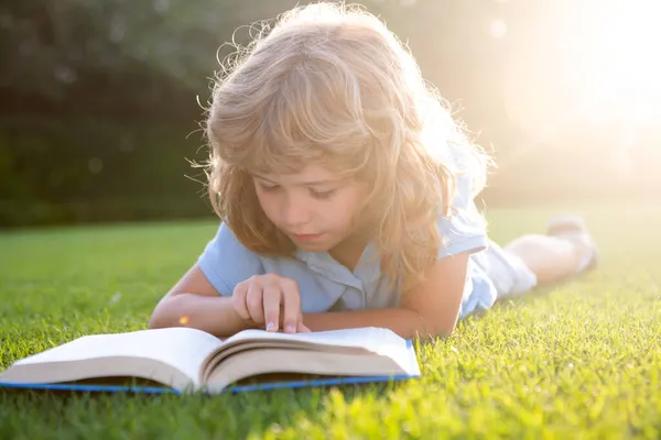 Çim arka planıyla ilgili güzel bir çocuk kitabı. Çocuklar parkta kitap okuyor.. — Stok fotoğraf