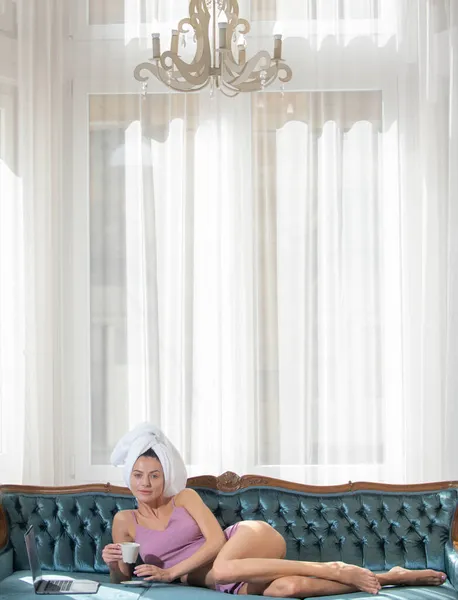 Κορίτσι αναπαύεται και ξαπλώνει σε άνετο καναπέ-κρεβάτι στην πολυτελή κρεβατοκάμαρα ένα εύκολο πρωινό. Ελκυστική σέξι γυναίκα χαλαρώνοντας φορώντας μπουρνούζια και πετσέτες στο ξενοδοχείο. — Φωτογραφία Αρχείου