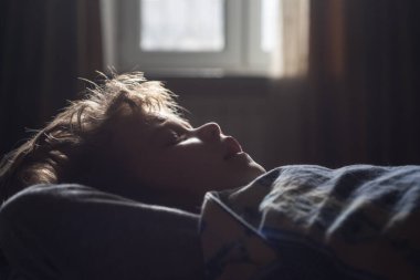 Yatakta uyuyan çocuk. Sabah ışıkları.