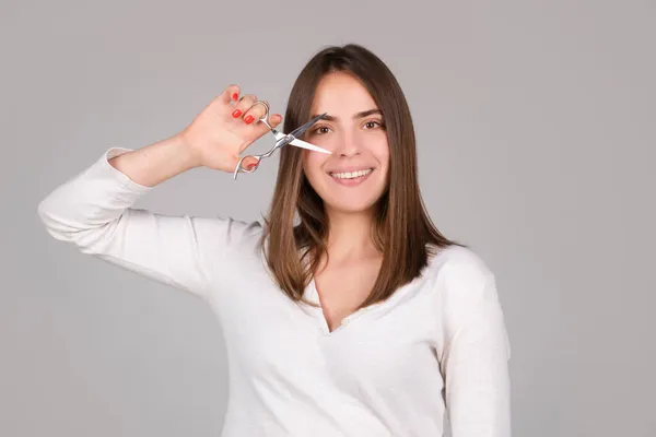 Mulher com tesoura cortando o cabelo. Menina bonita com cabelo liso com tesoura profissional. Conceito de cuidado. — Fotografia de Stock