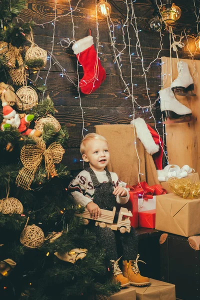 Roztomilé malé děti slaví Vánoce. Slavnostní svátek. Chlapče. Šťastné dítě s vánočním dárkem na dřevěném pozadí. Radostné dítě dívá na kameru ve vánocích doma. — Stock fotografie