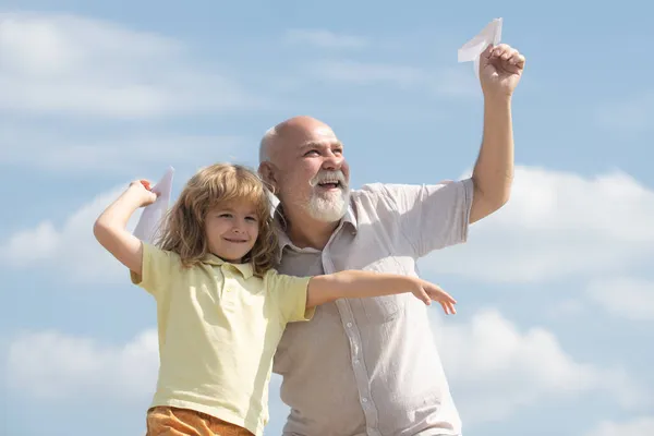 Avô e filho brincando com avião de papel de brinquedo contra o fundo do céu de verão. Menino com sonhos de voar. Relacionamento Familiar Avô e filho. — Fotografia de Stock