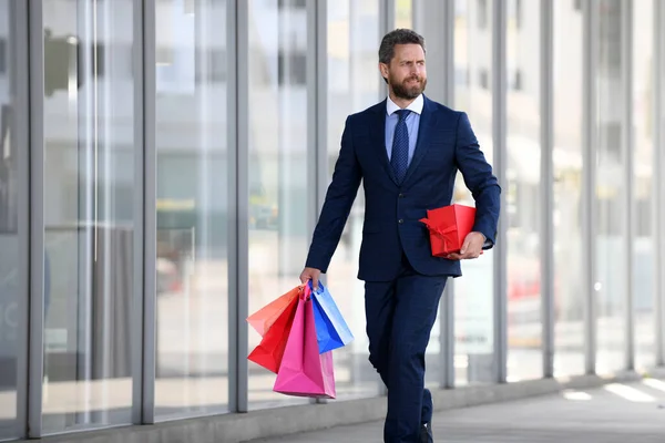 Επιχειρηματίας κρατώντας τσάντες για ψώνια και περπατώντας στο κατάστημα. Ψώνια και πληρωμή. Έννοια shopaholic ψώνια. — Φωτογραφία Αρχείου
