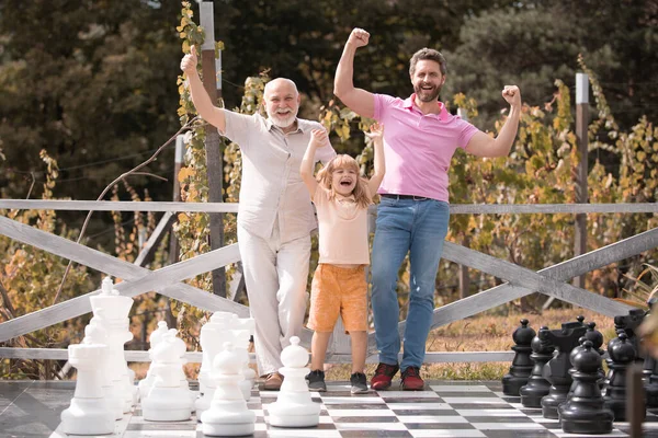 Familia de generación masculina junto con tres generaciones diferentes edades abuelo padre e hijo jugando ajedrez. Hombres en diferentes edades jugando ajedrez juego de mesa. Generación de los hombres concepto. —  Fotos de Stock